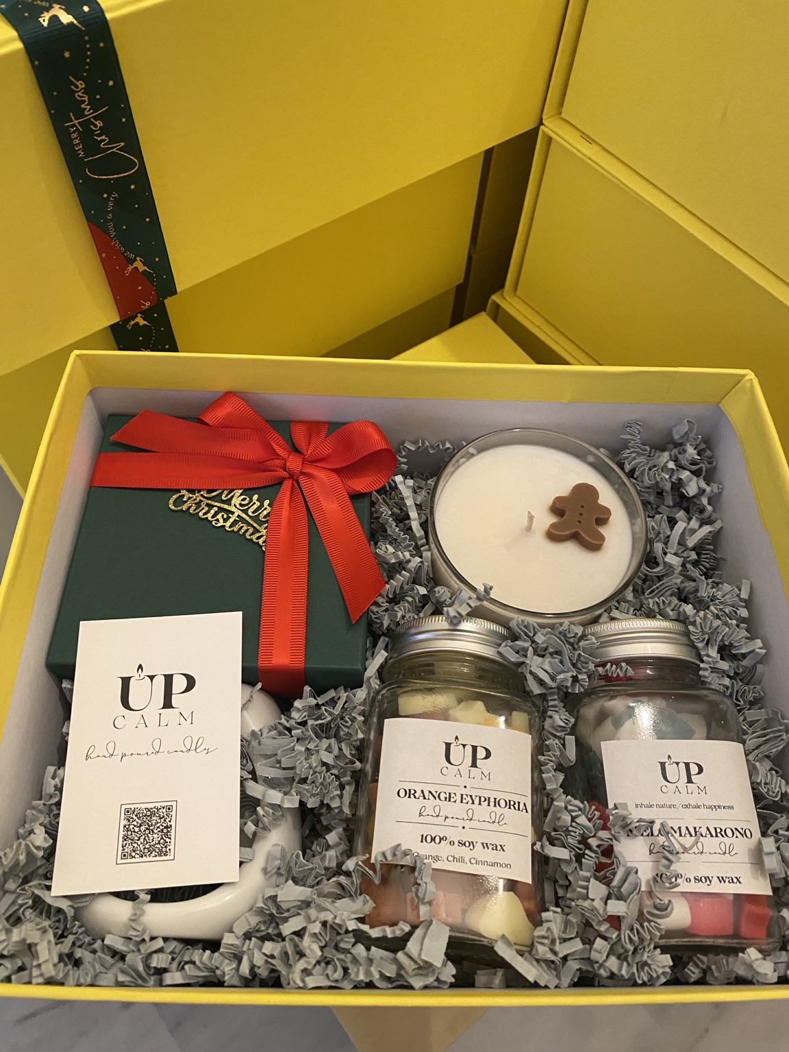 Χριστουγεννιάτικο gift box για τη Vorwerk: κίτρινο κουτί UPCALM με κερί, γιορτινές αρωματικές δημιουργίες και κόκκινη κορδέλα